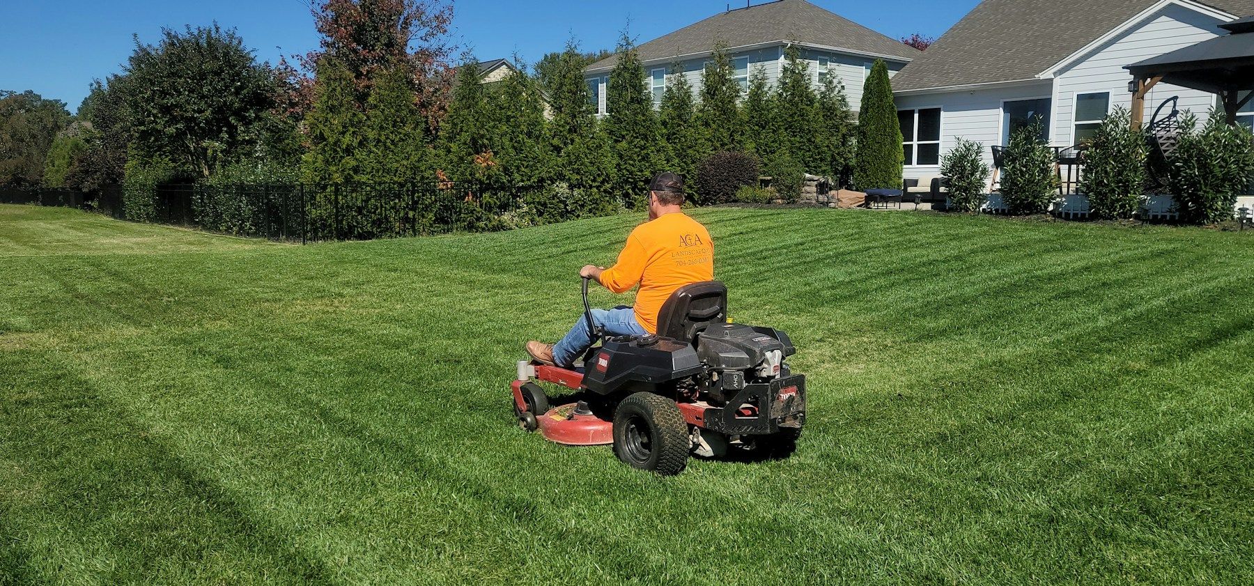 Riding mower cutting a lawn in even rows